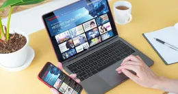 actu cin&eacute;ma  un homme fait son choix de vidéo en streaming via son ordinateur et son téléphone. 